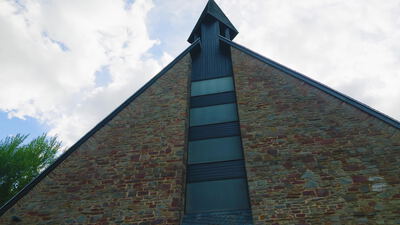 Giebel einer Kirche aus Bruchstein mit schmalem Fensterband Giebel einer Kirche aus Bruchstein mit schmalem Fensterband, Kirchengiebel, senkrechtes Fensterband und spitzer Giebel als