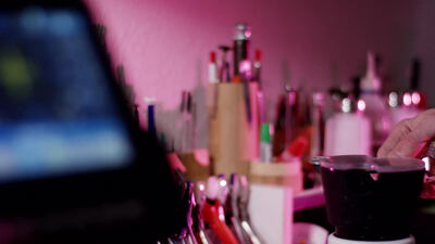 Schminktisch mit vielen Pinseln und Kosmetik im pinken Neonlicht