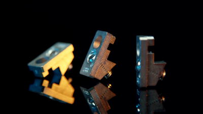 Metallteile mit Gewinde stehen auf spiegelnder schwarzer Oberfläche