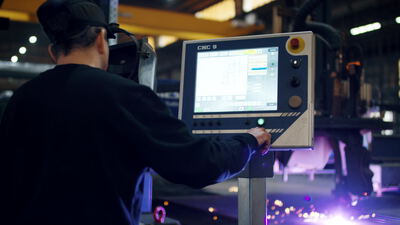 Arbeiter bedient die CNC Steuerung an einer Plasmaschneidanlage in der Fabrik