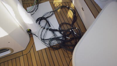 Schwarze Kabelbündel auf dem Teakdeck einer Yacht mit gelbem Stecker