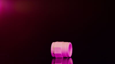 Rosafarbenes Metallfitting dreht sich vor dunklem Hintergrund