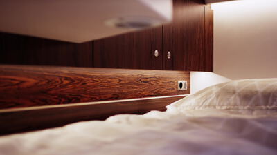 Gemütliches Bett mit dunkler Holzverkleidung und warmem Licht