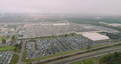 Luftaufnahme eines großen Industriegeländes mit Parkplätzen und Autobahn