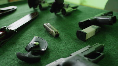 Pistolen Messer und Magazine auf grüner Auflage, Kurzwaffe, Taschenmesser und Munition als 4K Stockvideo