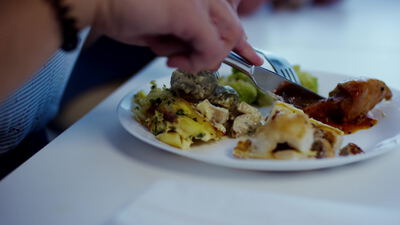 Person isst einen Teller mit Pasta und Gemüse im Restaurant