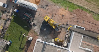 Luftaufnahme einer Baustelle mit gelbem Kran von oben