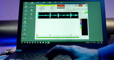 Techniker tippt am Laptop mit laufender Rohrprüfsoftware