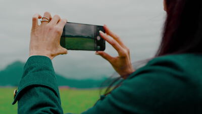 Frau fotografiert eine grüne Bergwiese mit dem Smartphone, Handy, Smartphone Fotografie und Handyfotografie als 4K Stockvideo