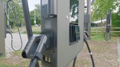 Ladekabel steckt in der Ladesäule für Elektrofahrzeuge im Park: Ladesäule, Elektroauto