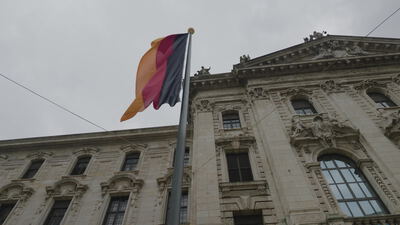 Deutsche Flagge weht vor einem historischen Gebäude mit Steinfassade