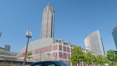 Messeturm und Messe Frankfurt erheben sich vor blauem Himmel