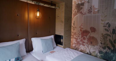 Blumentapete und gepolstertes Kopfteil zieren Hotelzimmer mit Stadtblick