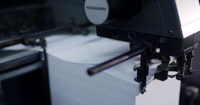 Bogenanleger einer Druckmaschine transportiert einen Stapel weißes Papier