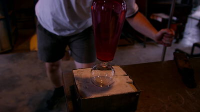 Glasbläser formt eine rote Vase auf der Holzform