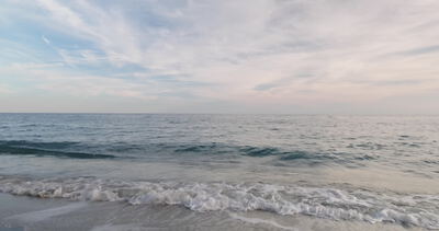 Sanfte Wellen laufen an einem Sandstrand unter zartem Wolkenhimmel aus Sanfte Wellen laufen an einem Sandstrand unter zartem Wolkenhimmel aus, Wellen am Strand, Brandung und brechende Welle als