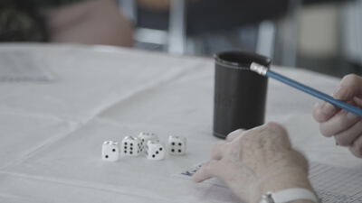 Hände spielen ein Würfelspiel mit Würfelbecher am Tisch
