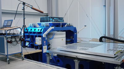 Industriemaschine mit blauer LED Beleuchtung bearbeitet Glasplatte in der Werkstatt