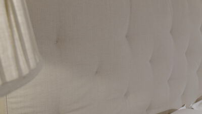 Gepolstertes Kopfteil mit Knopfheftung im warmen Lampenlicht, Bettkopfteil, Polsterung und Knöpfe als 4K Stockvideo