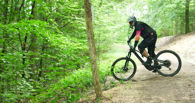 Mountainbiker fährt dynamisch über einen Trail im sommerlichen Wald