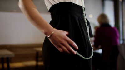 Frau im Café mit mintgrüner Perlenkette und Armreif