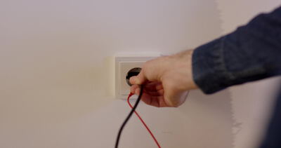 Elektriker prüft eine Steckdose mit Messspitzen
