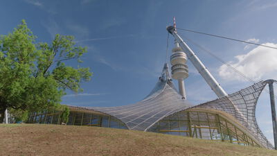 Zeltdach erstreckt sich weitläufig neben einem hohen Fernsehturm: Zeltdach, Fernsehturm