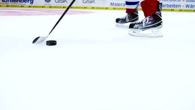 Eishockeyspieler führt den Puck mit dem Schläger über das Eis Eishockeyspieler führt den Puck mit dem Schläger über das Eis, Eishockeyschläger, Schlittschuhe und Eisfläche als 4K