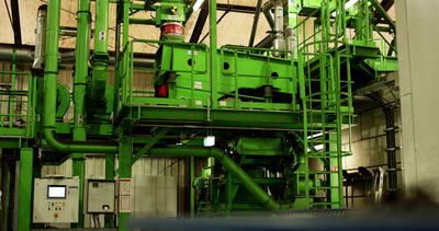 Steuerpult vor einer grünen Recyclinganlage in der Werkshalle