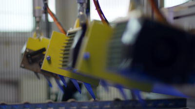 Gelb beschichtete Metallteile an der automatischen Beschichtungslinie Gelb beschichtete Metallteile an der automatischen Beschichtungslinie, Metallteile an Förderer, automatische