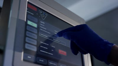 Behandschuhte Hand bedient Touchscreen an Verpackungsanlage