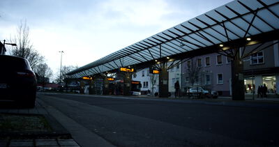 Überdachter Busbahnhof an einer Stadtstraße in der Dämmerung