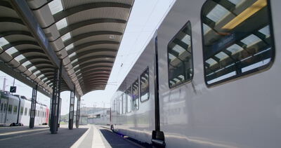Doppelstockzug am Bahnsteig unter geschwungenem Bahnhofsdach