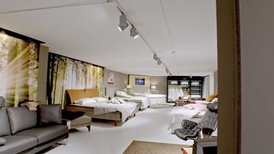 Helles Zimmer mit zwei Betten und Waldtapete neben einem Loungebereich