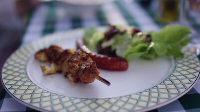 Gegrillter Fleischspieß mit Bratwurst und frischem Salat auf einem Teller