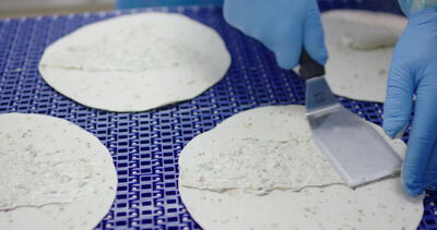 Sauce wird mit der Spachtel auf Fladenbrote für Wraps aufgetragen