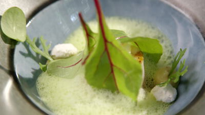 Grüne Schaumsuppe mit frischen Blättern in einer Schale, Suppe in Schale, frische Blätter auf Suppe und Cremetupfen als 4K