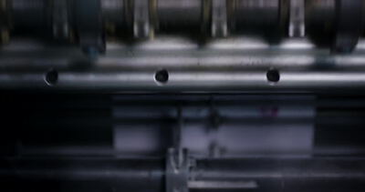 Papierbahn läuft durch die Walzen einer Zeitungsdruckmaschine