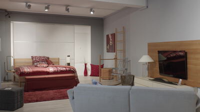 Schlafzimmer mit roter Bettwäsche und blauem Sofa neben einer Dekoleiter