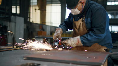 Metallarbeiter schleift eine Stahlplatte mit dem Winkelschleifer