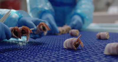 Speckröllchen werden von Hand auf blauem Gitterband gefertigt
