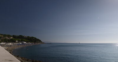 Bucht mit Badestrand und bewaldeter Landzunge unter klarem Himmel