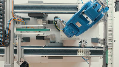 Blauer Industrieroboter arbeitet in einer automatisierten Fertigungszelle von oben