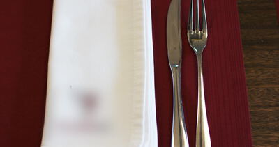 Gedecktes Restaurantgedeck mit Messer und Gabel auf roter Tischdecke