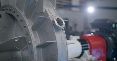 Nahaufnahme eines Schauglases am grauen Gussgehäuse einer Prozessmaschine