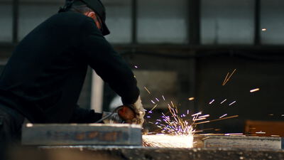 Handwerker schleift ein Metallteil auf der Werkbank in der Werkstatt