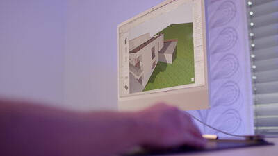 Designer arbeitet am Computer an einem 3D Hausmodell