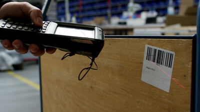 Handscanner erfasst den Barcode auf einer Holzkiste im Lager