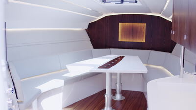 Moderner Yachtsalon mit klappbarem Esstisch und weißer Sitzgruppe
