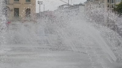 Springbrunnen sprüht Wasserfontänen vor Stadthäusern: Springbrunnen mit Fontänen, Wasserfontänen im Brunnen
